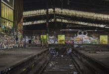 Große Lokhalle mit Gleisgruben und Graffitimuralen mit Grünblick durch Fenster im Lost Place
